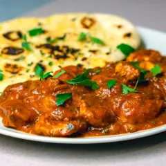 En krämig chicken masala med naanbröd, garnerad med färsk persilja. En smakrik indisk rätt.