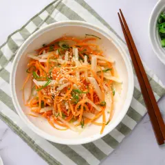 En fräsch sallad med strimlad daikon, morot och salladslök, toppad med sesamfrön. Ett enkelt daikon recept.