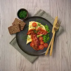 En härlig omelett i ugn med knaperstekt bacon, färska tomater, sallad och grovt bröd. Serveras med gräslök.