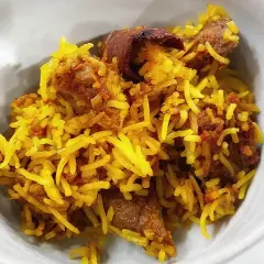 En skål med gyllene ris och möra bitar av lammkött. En härlig lamm biryani som ser otroligt god ut.
