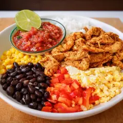 En färgglad bowl med ris, svarta bönor, majs, kyckling, salsa, lime och äggröra. Ett perfekt bowl recept för en snabb och god middag.