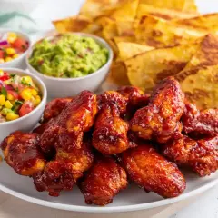 Saftiga kycklingvingar i ugn med tortillachips, guacamole och salsa. Perfekt för en festlig middag!