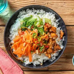 En läcker donburi med kyckling, ris, strimlad morot, pak choi och jordnötter.
