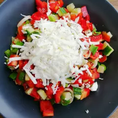 En fräsch sopska salata med hackad tomat, gurka, paprika och lök, toppad med riven ost.