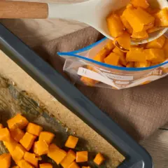 Förbereder butternutpumpa för ett recept. Tärnad pumpa läggs från en sked till en fryspåse.