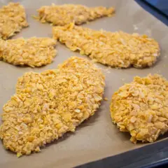 Flera bitar cornflakes kyckling ligger på en bakplåt.