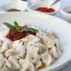En skål med manti, små dumplings med yoghurt, tomatsås och mynta. Ett utsökt manti recept att prova!