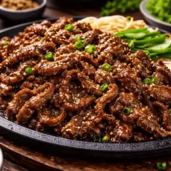 En stor portion saftig, marinerad biff med sesamfrön och salladslök, perfekt för ett bulgogi recept. Serveras med nudlar och grönsaker.