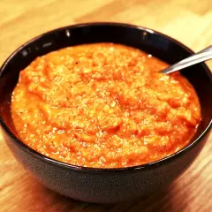 En skål med krämig ajvar, perfekt för ditt ajvar recept. En sked vilar i den orangea röra.