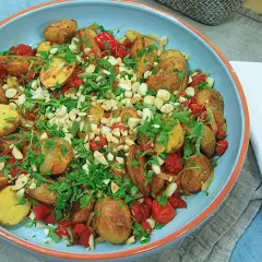 En härlig varm potatissallad med rostade potatisar, tomater och nötter, toppad med färsk persilja. Perfekt som tillbehör.