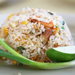 En hög med stekt ris, perfekt för risrester recept. Garnerad med lime, salladslök och en bit gurka.