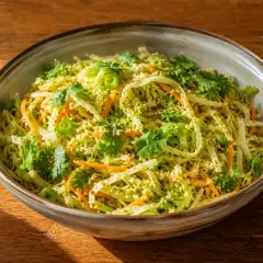 En skål med fräsch asiatisk kålsallad med strimlad kål, morötter, koriander och sesamfrön.