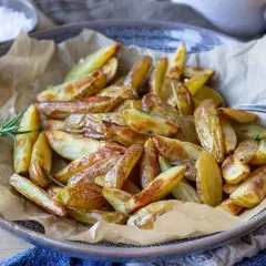 Klyftpotatis i airfryer, gyllene och krispiga, serverade med färsk rosmarin. Perfekt som tillbehör!