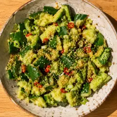 En skål med asiatisk gurksallad, toppad med sesamfrön, chili och salladslök.