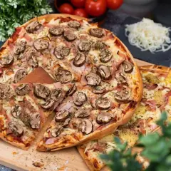 En härlig liba pizza med champinjoner och skinka, redo att avnjutas. Bredvid ligger en annan pizza med ananas och skinka.