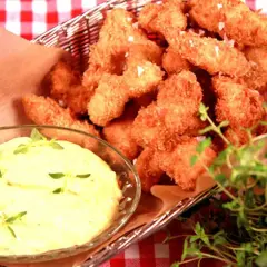 Korg med gyllene chicken nuggets, serverade med en krämig dipp och färska örter.