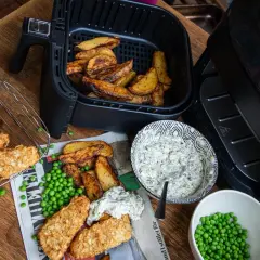 Krispiga fiskpinnar och klyftpotatis från airfryern, serverade med ärtor och en krämig dipp. Ett perfekt airfryer recept!