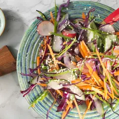 En färgglad sallad med strimlad rödkål, morot, rädisor och gurka, toppad med sesamfrön. Ett perfekt salladskål recept för en krispig och fräsch måltid.