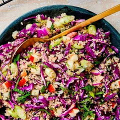 En färgstark couscous sallad med rödkål, äpple och färska örter. En gyllene sked vilar i den fräscha rätten.