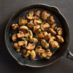 Stekta champinjoner i gjutjärnspanna, perfekt för ett snabbt svamp recept. Garnerade med persilja.