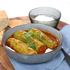 Kousa mahshi, fyllda squash i en mustig tomatsås, serveras med färskt bröd och en skål yoghurt.