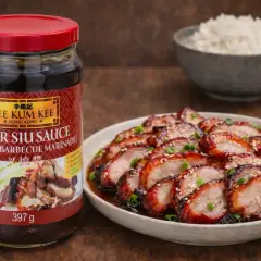 En burk Lee Kum Kee Char Siu Sauce, en enkel marinad, bredvid en tallrik med skivat grillat fläsk och en skål ris.
