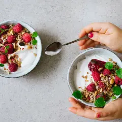 Två skålar med kokosyoghurt, hallon, granola och mynta. Perfekt för ett enkelt kokosyoghurt recept.