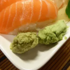 Närbild på sushi med lax och ris, serverad med två klickar grön wasabi. Perfekt för ditt wasabi recept!