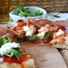 En skiva pinsa med prosciutto, mozzarella och ruccola. En härlig pinsa topping som ser utsökt ut.