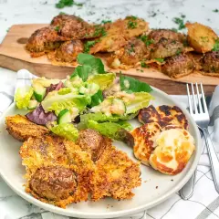 Krispiga, ugnsbakade potatisar med ostpanering serveras med en fräsch sallad och grillad halloumi. En härlig måltid!