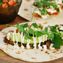 En närbild på en taco med köttfärs, avokado, koriander och en vit sås. Perfekt för ett tacokrydda recept!