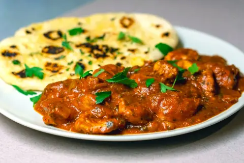 En krämig chicken masala med naanbröd, garnerad med färsk persilja. En smakrik indisk rätt.