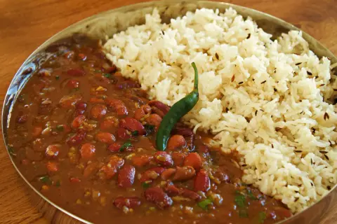 En skål med rajma chawal, en indisk rätt med kidneybönor i en kryddig sås och ris, toppad med en grön chili.