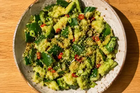 En skål med krossad gurka, toppad med sesamfrön, chili och salladslök. Ett enkelt gurka recept för en fräsch sidorätt.