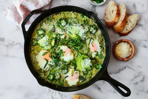 Grön shakshuka med ägg, avokado och jalapeño i gjutjärnspanna. Perfekt för ett smakrikt shakshuka recept.