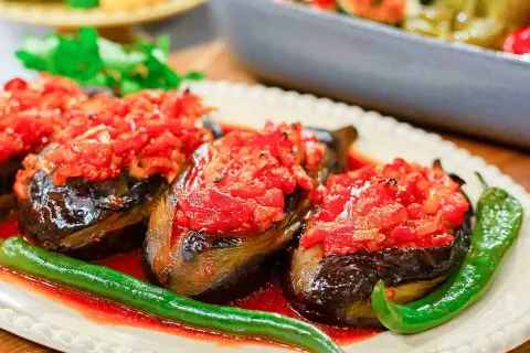 Tre auberginehalvor fyllda med tomat och paprika, serverade med gröna chilis. En härlig imam bayildi.