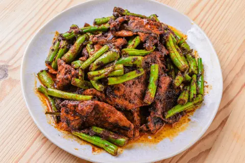 En tallrik med Pad Khing, en smakrik thailändsk rätt med strimlat fläsk och gröna bönor i en kryddig sås.