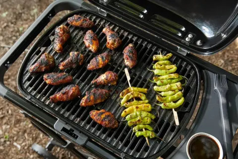 Grillens dag firas med saftiga kycklingvingar och grillade paprikor på en portabel grill.