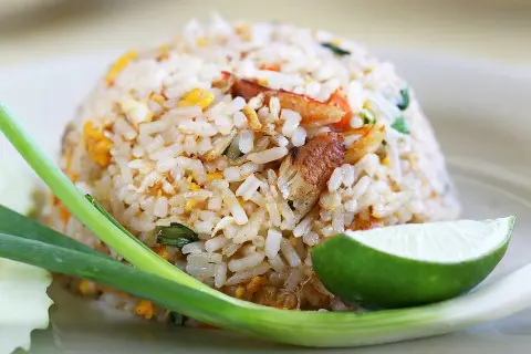 En hög med stekt ris, perfekt för risrester recept. Garnerad med lime, salladslök och en bit gurka.