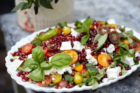 En färgglad sallad med granatäpple, tomater, fetaost och basilika, perfekt som sallad till grillat.