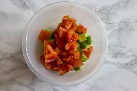 Tärnad tomat och gurka i en skål, redo att bli en fräsch sallad shirazi.