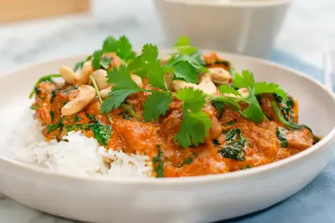 En krämig palak chicken med ris, toppad med cashewnötter och färsk koriander. En smakrik indisk rätt.