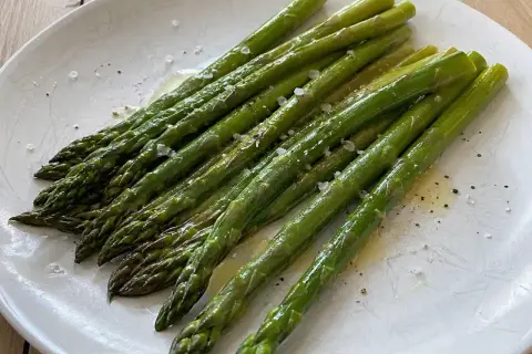 En tallrik med perfekt kokt sparris, lätt oljad och strödd med flingsalt och peppar. En enkel och god rätt att koka sparris till.
