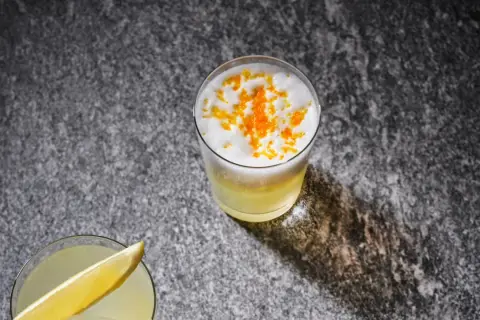 Två uppfriskande drinkar, en med citronskiva, den andra toppad med skum och yuzu-zest. Perfekt för ett yuzu recept.