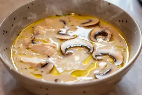 En ångande skål med krämig tom kha gai, fylld med möra kycklingbitar och saftiga champinjoner.