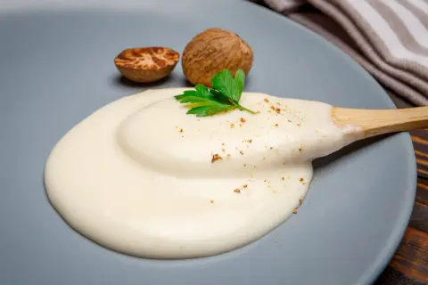 Krämig bechamelsås på en tallrik, med muskotnötter och persilja. Perfekt för att frysa in och använda senare.