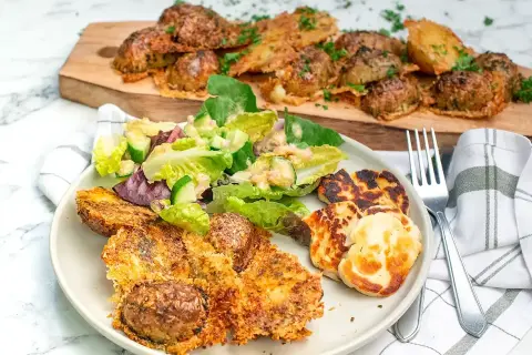 Krispiga, ugnsbakade potatisar med ostpanering serveras med en fräsch sallad och grillad halloumi. En härlig måltid!