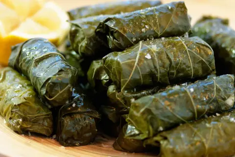 En hög med sarma, vindruveblad fyllda med ris och kryddor, serveras med en citronklyfta. Ett utsökt sarma recept!