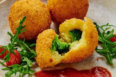 Krispiga bollar med potatis och broccoli, panerade i panko. Serveras med tomater och ruccola.