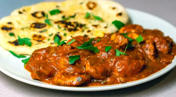 En krämig chicken masala med naanbröd, garnerad med färsk persilja. En smakrik indisk rätt.